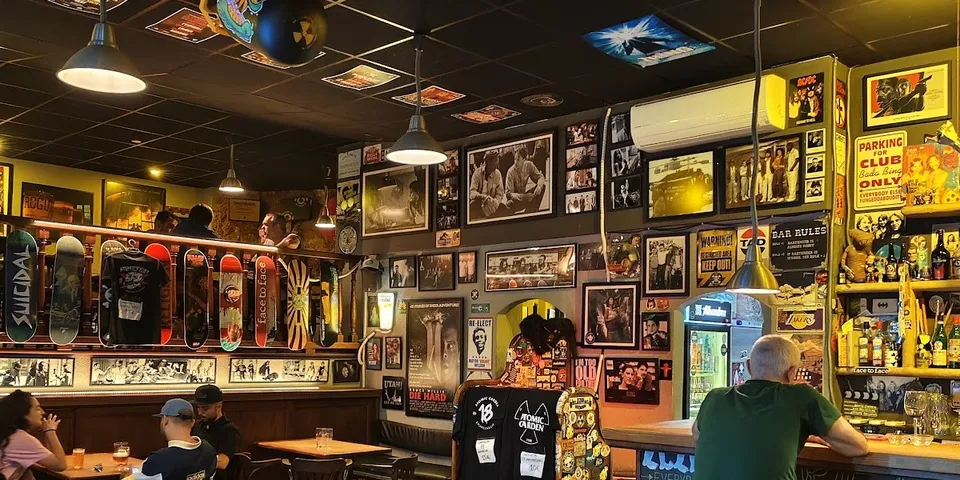 Interior de la cervecería Atomic Garden en Palma, con paredes llenas de pósters de cine y rock, taburetes de madera y ambiente craft