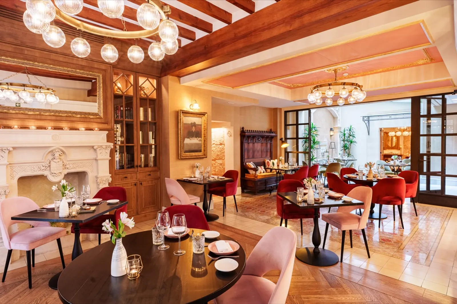 Restaurante de Cabau Hotels con interior elegante, mesas dispuestas, chimenea y arañas de cristal