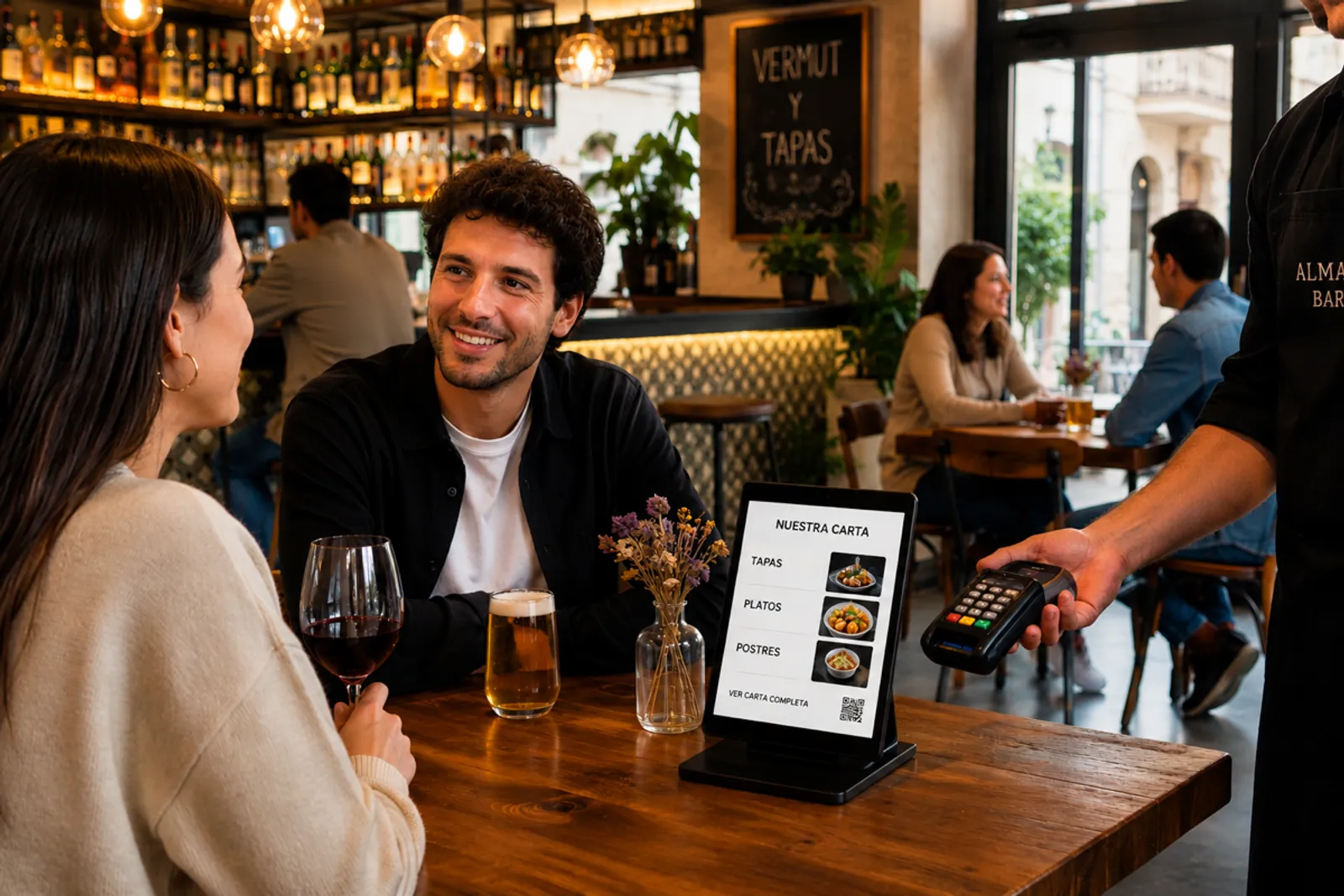 Vista de un bar moderno español con clientes y tecnología visible — carta digital en mesa, datáfono inalámbrico